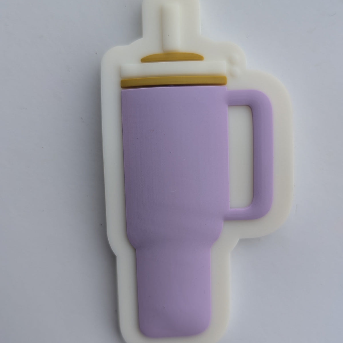 A small novelty item shaped like a simplified baby bottle, featuring a lavender purple body, a white outer outline, and a small gold accent near the left side, photographed on a plain white surface.