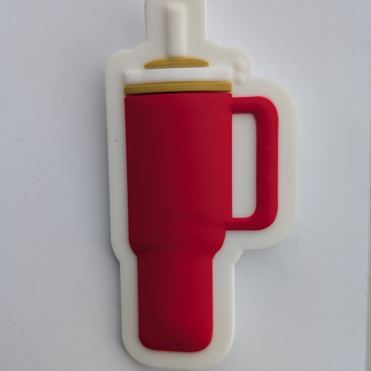 A red insulated tumbler mug with a white handle and lid, shown from a top-down view on a white sheet of paper.